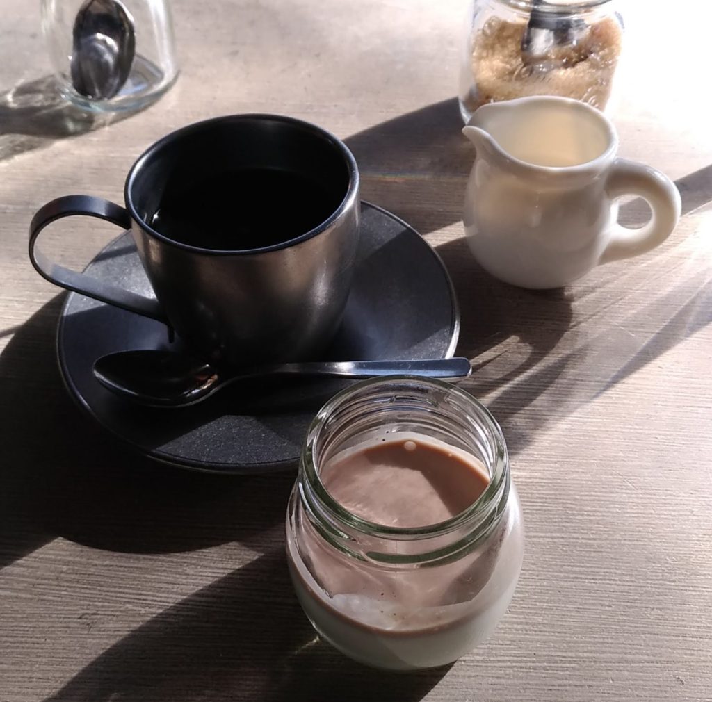光が強すぎて影が濃い(内側が黒色のコーヒーカップとプリン)