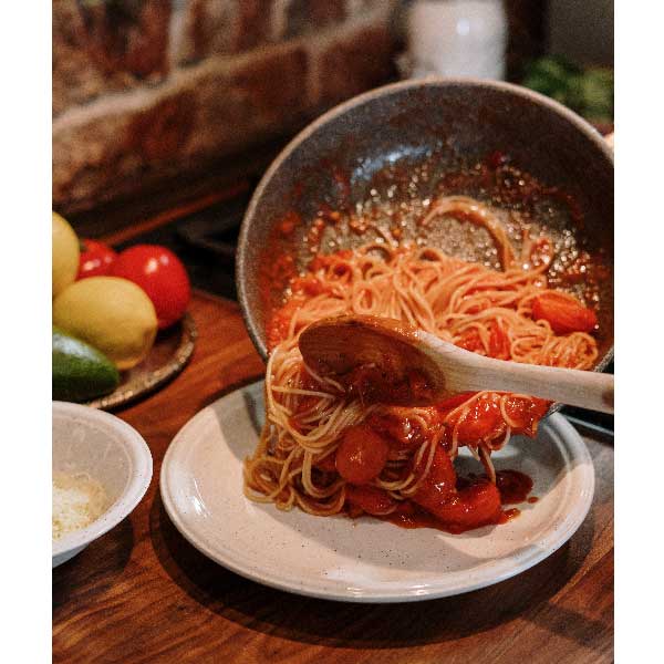 パスタとソースを和えている画像